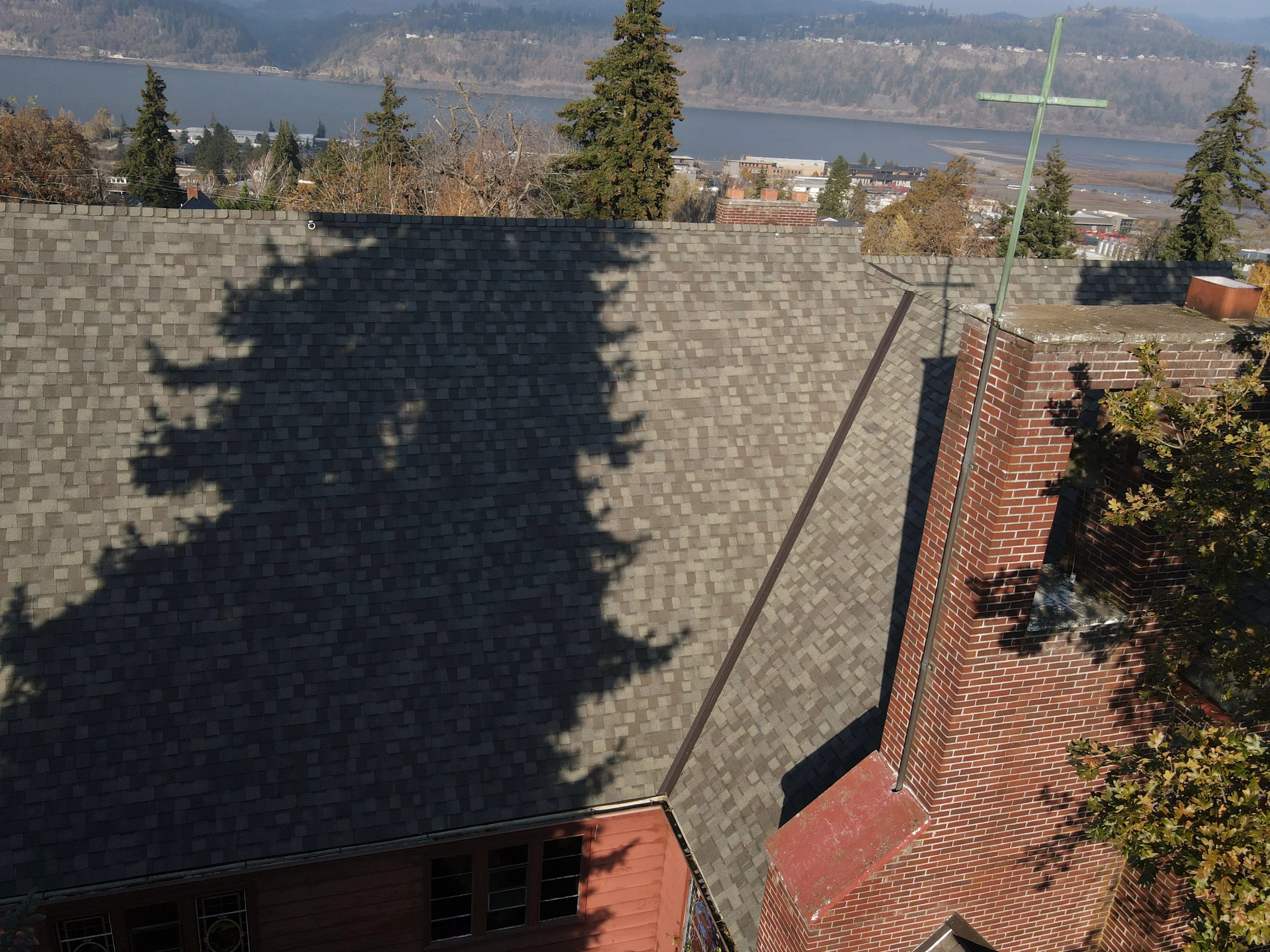 Charcoal gray asphalt shingle roof with metal flashing installed on brick chimney structure