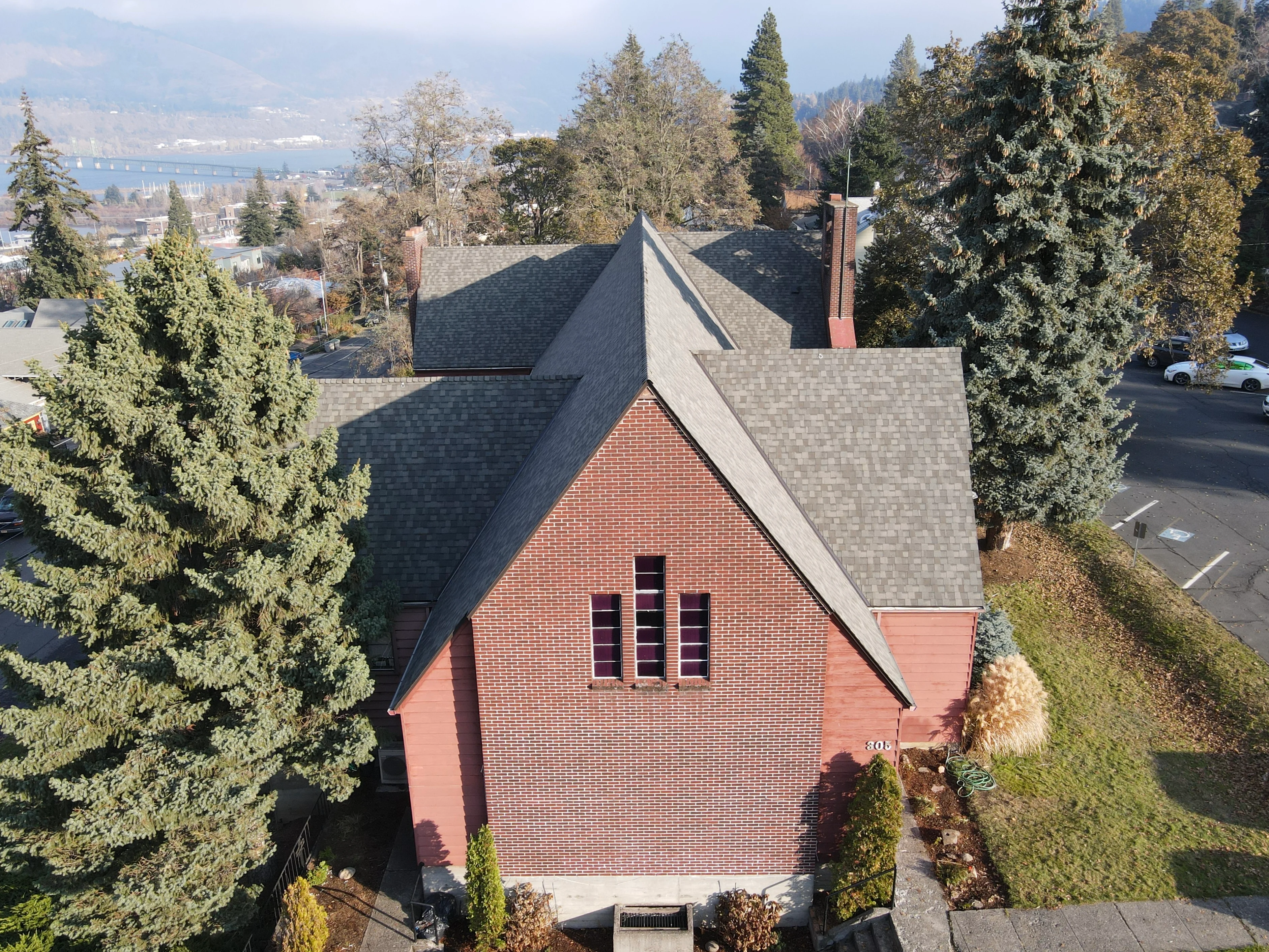 Aerial view of brick home with new charcoal gray architectural shingle roof and brick chimneys