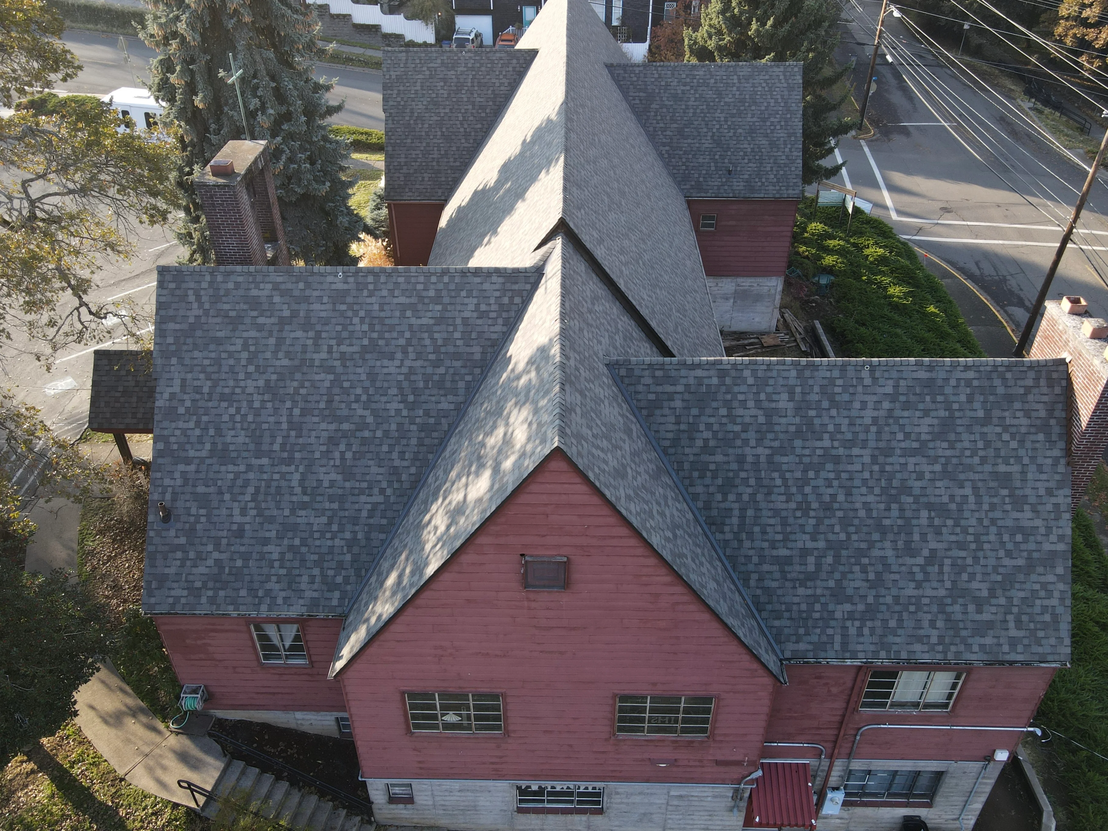 Aerial view of slate gray architectural shingle roof on red brick home with multiple gables