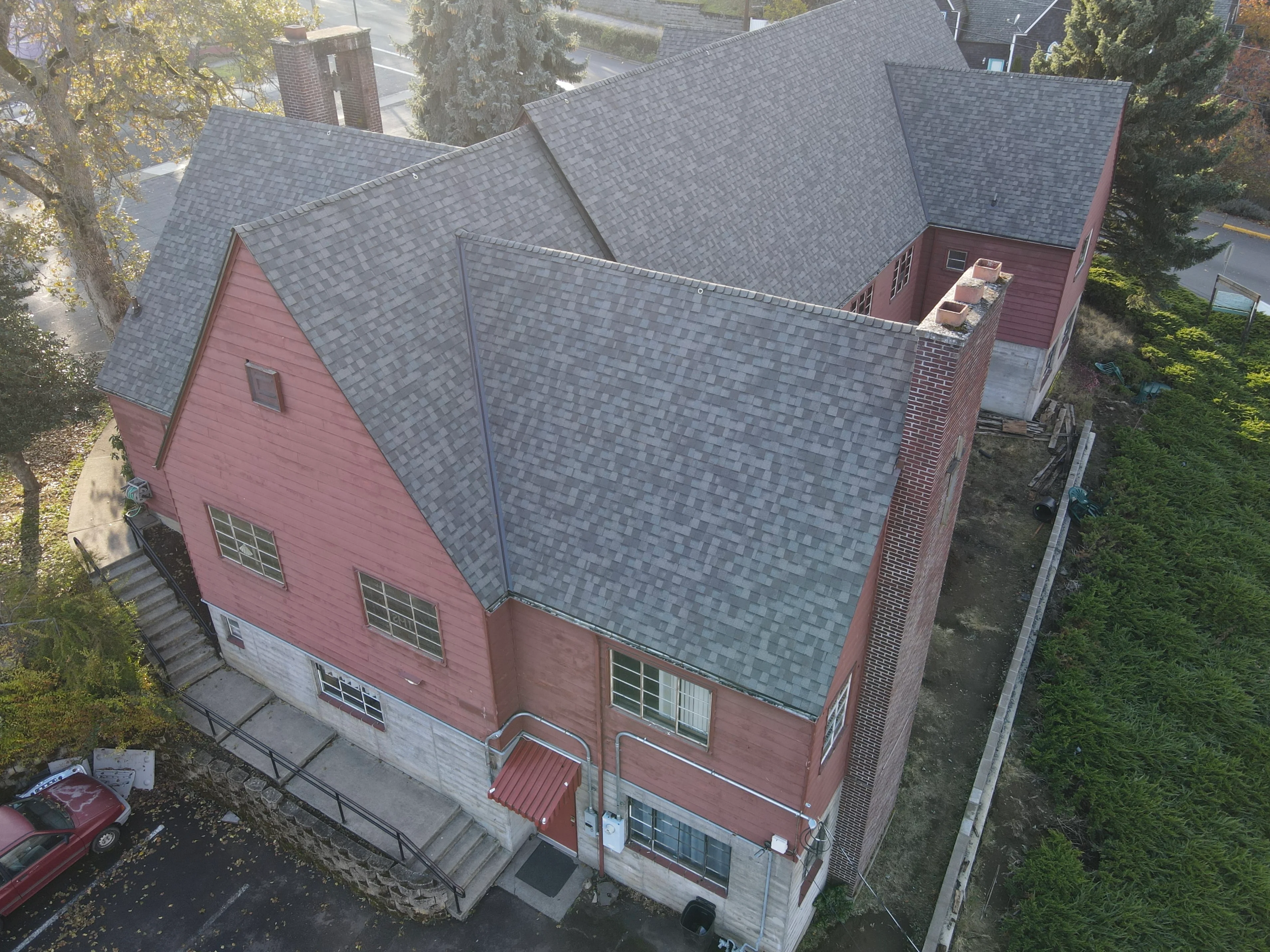 Gray architectural shingles installed on multi-plane residential roof with brick and siding exterior