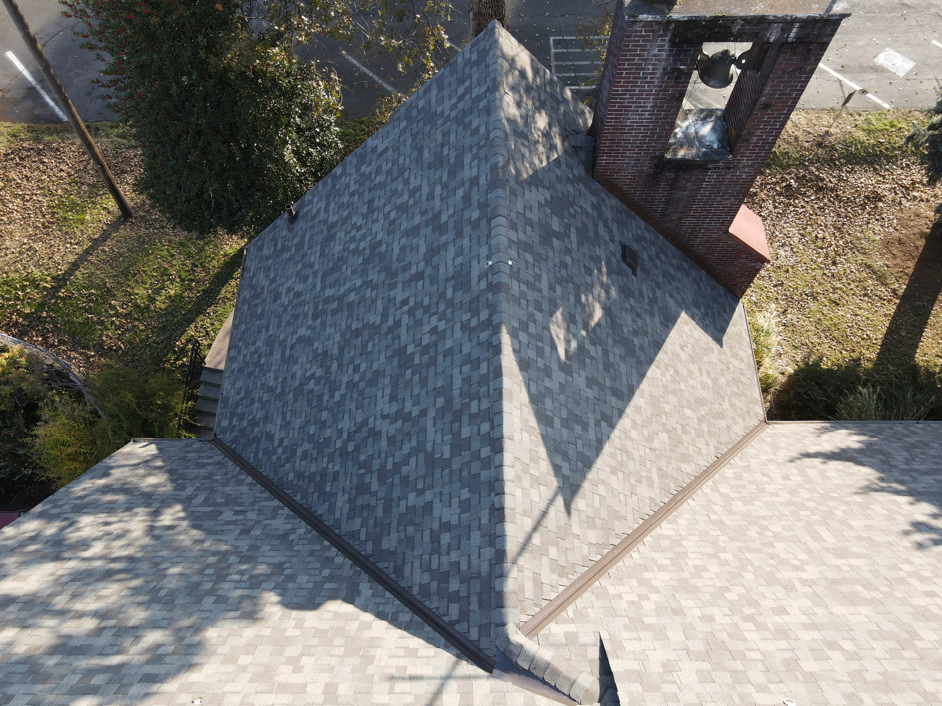 Aerial view of new charcoal gray architectural shingle roof with multiple planes and integrated guttering