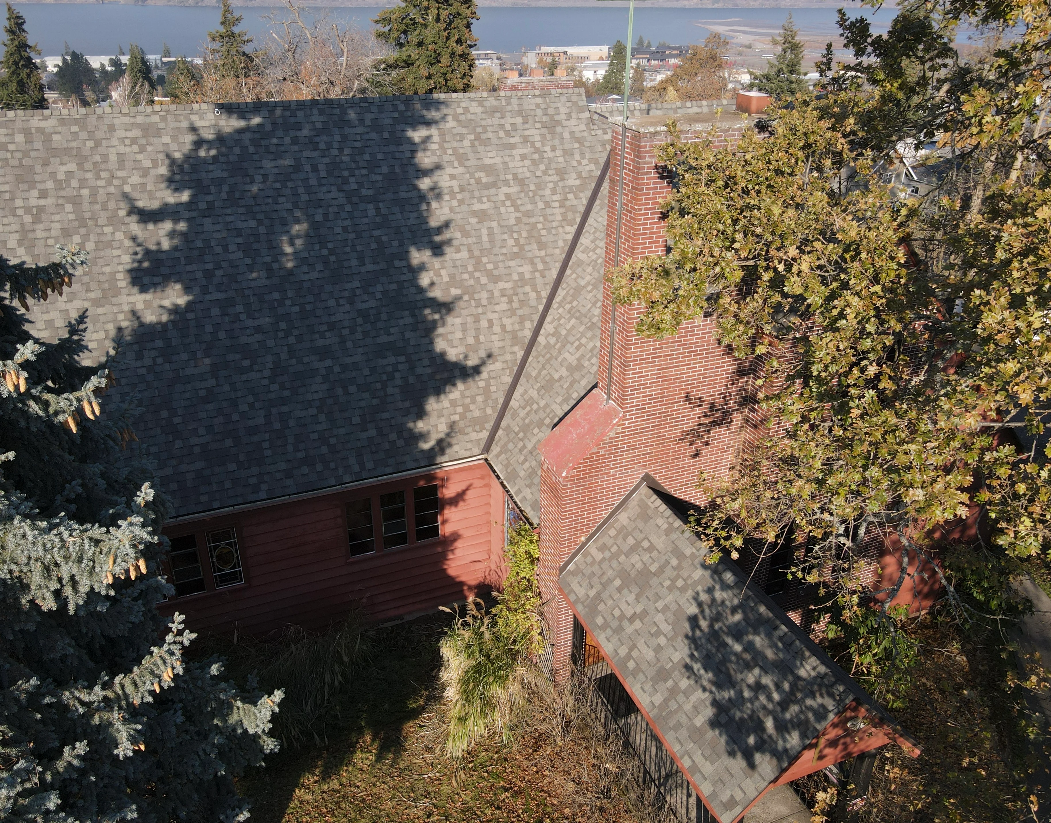 Charcoal slate shingles on multi-level brick home with dormers and complex roof planes